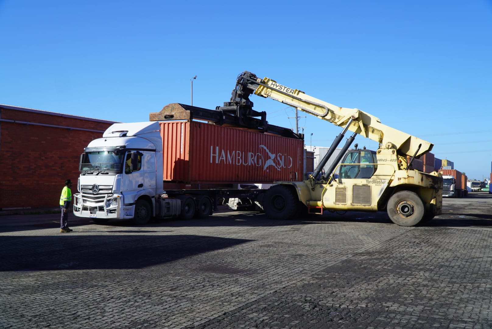 Reach stacker transferring shipping container onto truck at Datts Logistics Melbourne